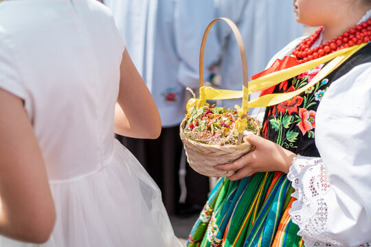 Girls in traditional Polish folk costumes throwing fresh flower petals during Łowicz Corpus Christi procession	
