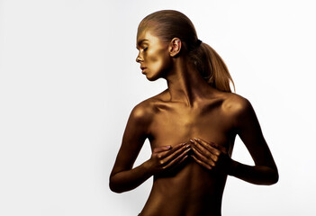 Gold nude body paint. Sexy naked model in gold paint pose on studio isolated background. Beauty...
