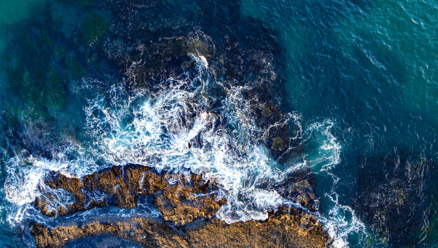 Turquoise sea water with reef. Ocean surf. Dramatic sea waves on reef. Coastal rocks and sea surf. Aerial view of ocean waves. Sea surface. Drone shot of beauty rocky coastline.