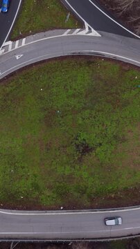 Roundabout Serenity: Aerial shot of a serene roundabout with the smooth curves of asphalt winding gracefully around a lush patch of green. A lone vehicle navigates the circular path.
