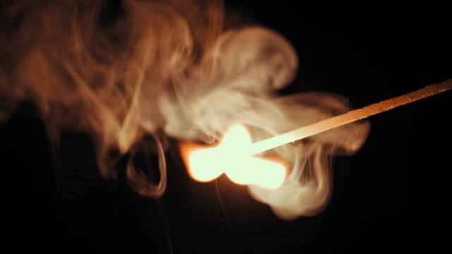 Burning matchstick on black background