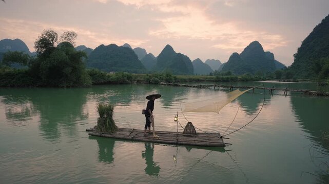 Rural fisherman fishing from bamboo raft on river in Phong Nam Valley, Vietnam