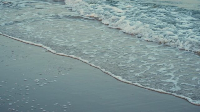 Soft sea foam wave on calm beach during evening light