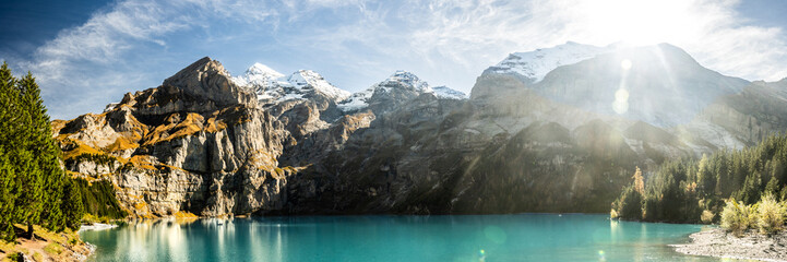 Obraz premium Panorama Of Sunburst Over The Blue Water of Oeschinen Lake In The Swiss Alps
