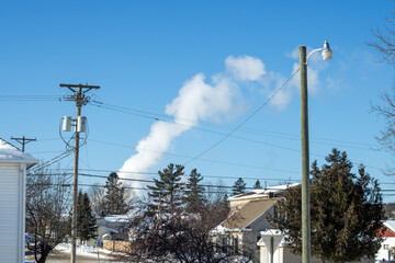 Obraz premium Power lines and steam from an industrial chimney in winter