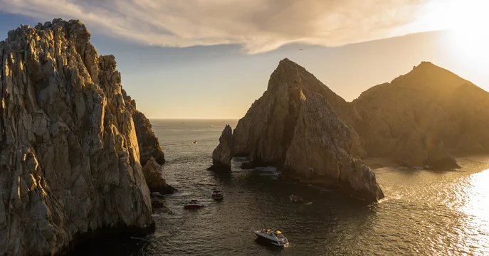 Aerial panoramic view of El Arco de Cabo San Lucas, mar de cortés, during the golden hour with a blue cloudy sky as background.