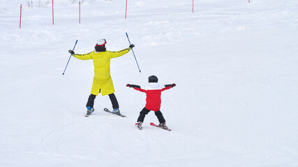 A children's ski instructor conducts an individual lesson in a playful manner with a child at a ski resort.