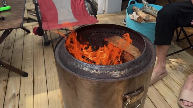Having fire in metal smokeless drum burn barrel on DIY wooden deck in studio flat in New Zealand.