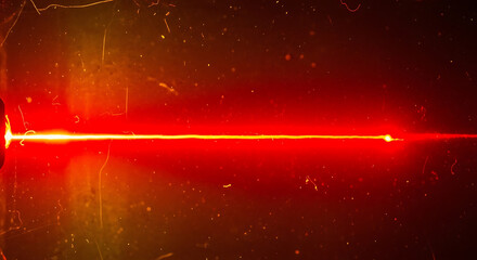 A bright red laser beam cutting through darkness