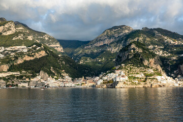 Fototapeta premium Pastel villages tumble down Amalfi's sheer cliffs like sun-kissed confetti, their terraced lemon groves and ochre tiles aglow in the amber hush of twilight