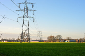 Electricity Pylons and Power Lines Crossing Green Agricultural Fields Under Blue Sky © Rogier van Bunnik