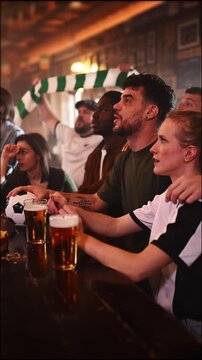 Diverse soccer fans celebrating a goal in a pub
