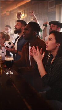 Multiethnic friends cheering for their team in a crowded sports bar