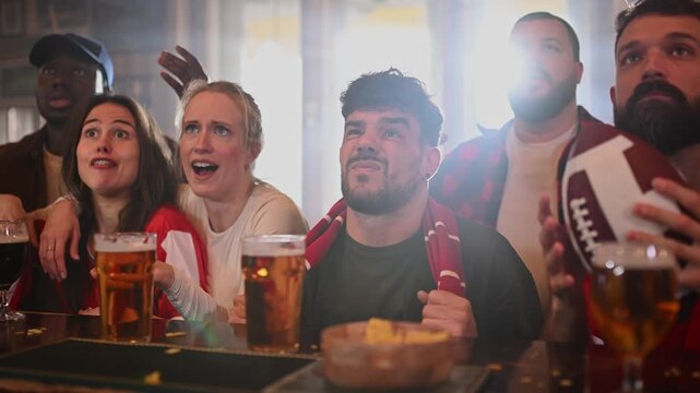 Disappointed sports fans watching a football game in a bar
