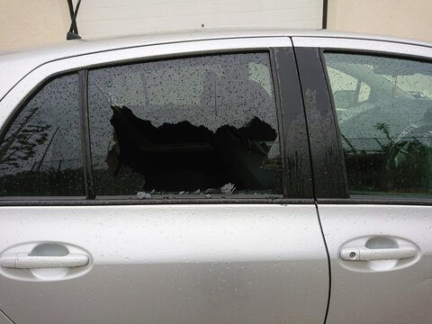 Car break in with shattered smashed side window. Economic downturn fuels street criminality, shattered vehicle glass signaling hardship and criminality rise.