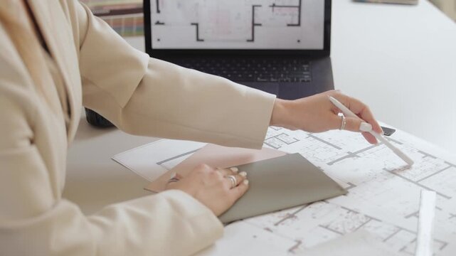 Architect planning: hand reviewing diagrams and using swatches at computer desk.