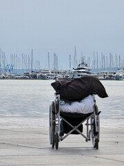 Fototapeta premium Empty Wheelchair at the Harbor with Luxury Yachts and Boats in the Background