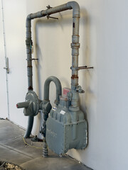 Grey Compressed natural gas pump and valves on exterior building wall