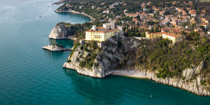 Aerial panoramic view of Duino Castle on high limestone cliffs with Adriatic sea and coastal village Friuli Venezia Giulia Italy