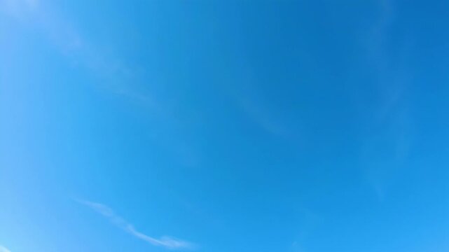 A wide video looking up into a pristine blue sky with a smooth cerulean to sky blue gradient, delicate cirrus clouds, and slow push-in movement. Concept of boundless potential