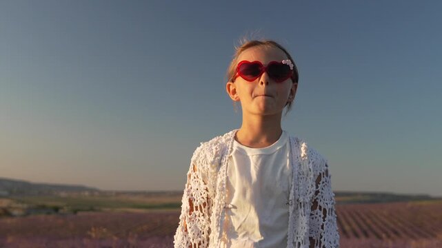 Child lavender sunglasses girl blowing kiss in blooming field at sunset