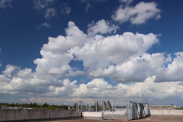 Obraz premium widok z parkingu na dachu wieżowca. białe chmury i błękitne niebo.