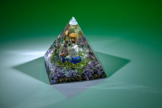 Orgonite pyramid with a small bottle of silver against a colorful background.