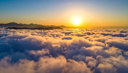 Aerial view of sunrise above sea of clouds, golden light bathes landscape