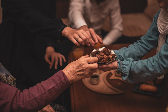 Hands Sharing Dates During Ramadan Celebration Close-Up View of Generational Muslim Family Members Enjoying Traditional Food Together During Iftar Meal at Home