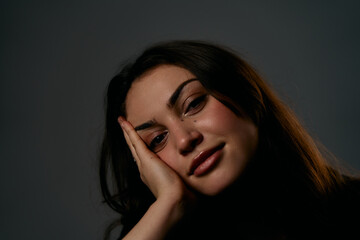 Fototapeta premium Contemplative Portrait Of A Woman Resting Her Head On Her Hand Under Soft Studio Lighting