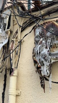 Damaged and melted plastic electrical wiring and junction box on a building wall. The aftermath of a dangerous fire showing burnt cables