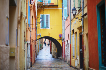 Fototapeta premium Vibrant view of colorful buildings with blue shutters and national flags in a coastal Mediterranean town