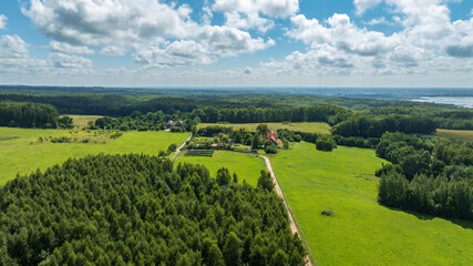 Obraz premium Aerial homestead with red roof amid meadows and mixed forest