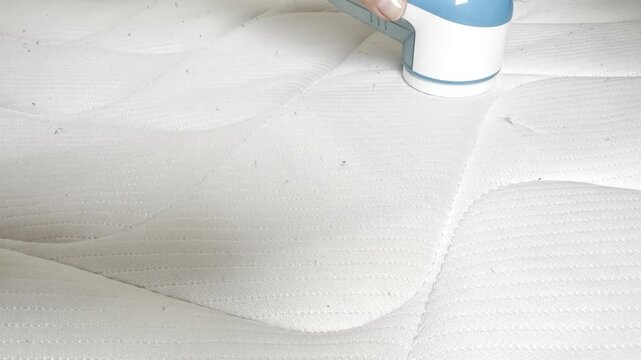 A hand holds a lint remover, a clothes cleaning gadget