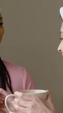 Vertical video: Offering mug, braided friend holding coffee by window with towel, hoops, copy space