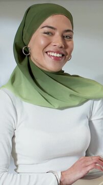 Vertical video: Camera on, woman in green hijab smiling, engaging camera at table, hands on laptop
