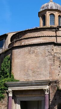 ancient roman brick rotunda small domed cupola cross beside medieval buildings lone marble column creeping greenery tempio del divo romolo close view rome italy empire emperor 