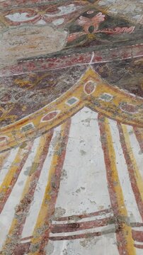 weathered roman fresco fragment ornate draped garlands floral motifs faded tones cracked plaster reflects centuries tempio del divo romolo rome italy empire emperor ancient art 