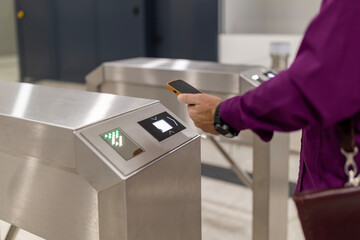 Person using smartphone for contactless subway access at turnstile