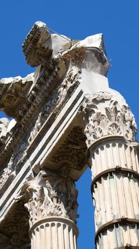 looking partially collapsed ancient roman columns entablature corinthian capitals decorative friezes stand against cloudless sky foro di cesare upward shot rome italy empire 