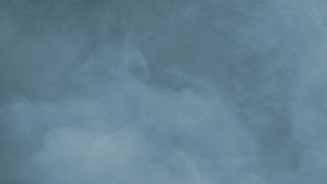 Slowly Moving Fog Blue Tint on Black 4K Loop features slow rolling fog or smoke with a blue tint in a loop.