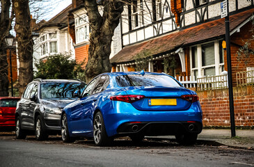 Naklejka premium Blue sports car parked on residential city street with striped detailing in front view