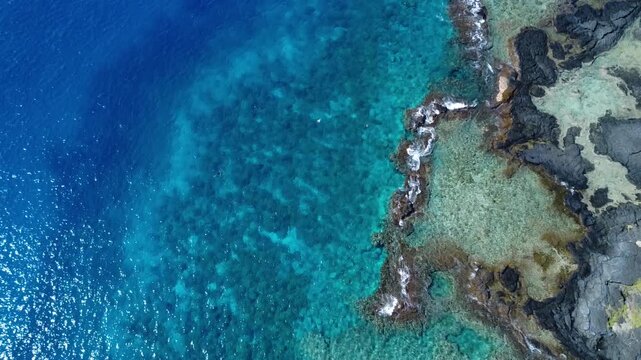 Drone looking down at beautiful tropical ocean lava rock coastline in Hawaii