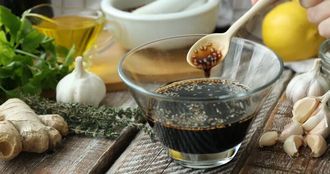 Woman making soy sauce marinade at wooden table, closeup
