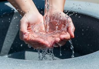 Fototapeta premium Close up of water splashing in cupped hands for wudu