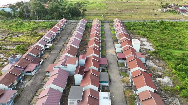 An aerial view showing rows of neatly arranged houses in a suburban neighborhood. The surrounding green fields highlight the modern lifestyle of the neighborhood.