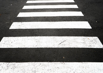 pedestrian crossing road. Crosswalk stripes on neighborhood street. Zebra cross. Pedestrian crossing, white stripes on black asphalt, road markings, traffic rules. Graphic design texture.