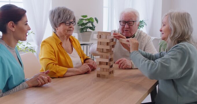 Jenga playing fun, memory boosting game, active seniors play friends, mentally challenging activities to help cognitive abilities, social contact in recreational club, retirement house, retired people
