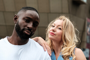 Interracial couple posing with woman leaning on man's shoulder