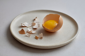 Egg shell with yolk on a plate after breaking during breakfast preparation in a kitchen setting